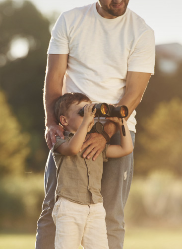 Photo d'un papa qui montre les jumelles a son fils